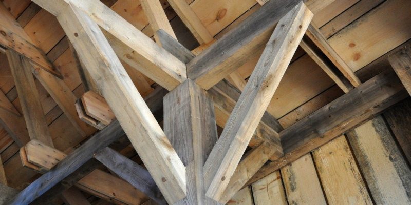 Image of a wooden post and beam construction with diagonal knee bracing supports for each beam.