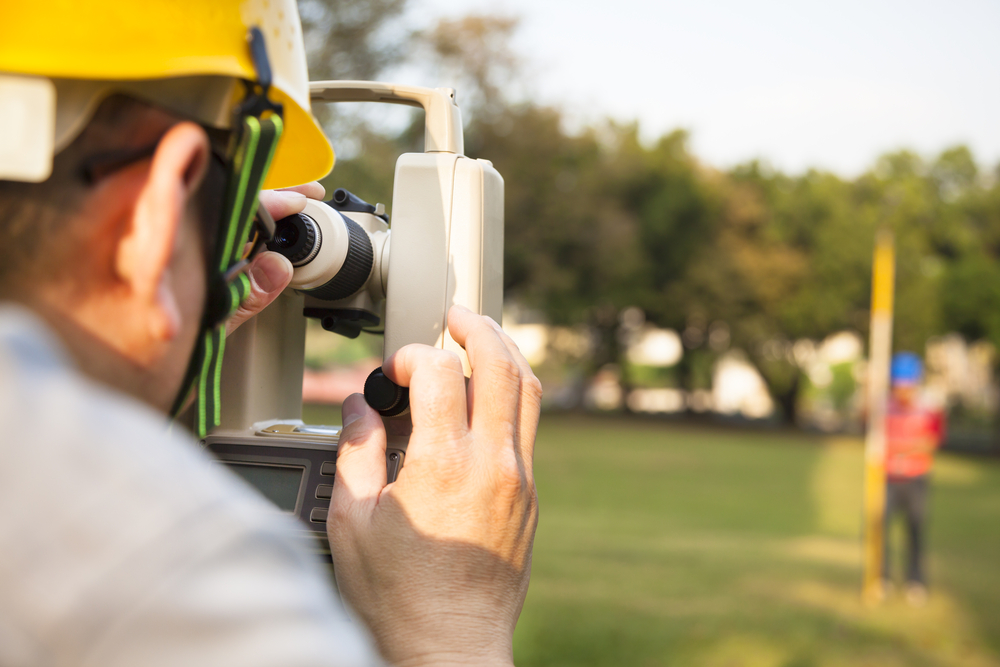 Land surveyor viewing a leveling rod through a surveyor's transit.